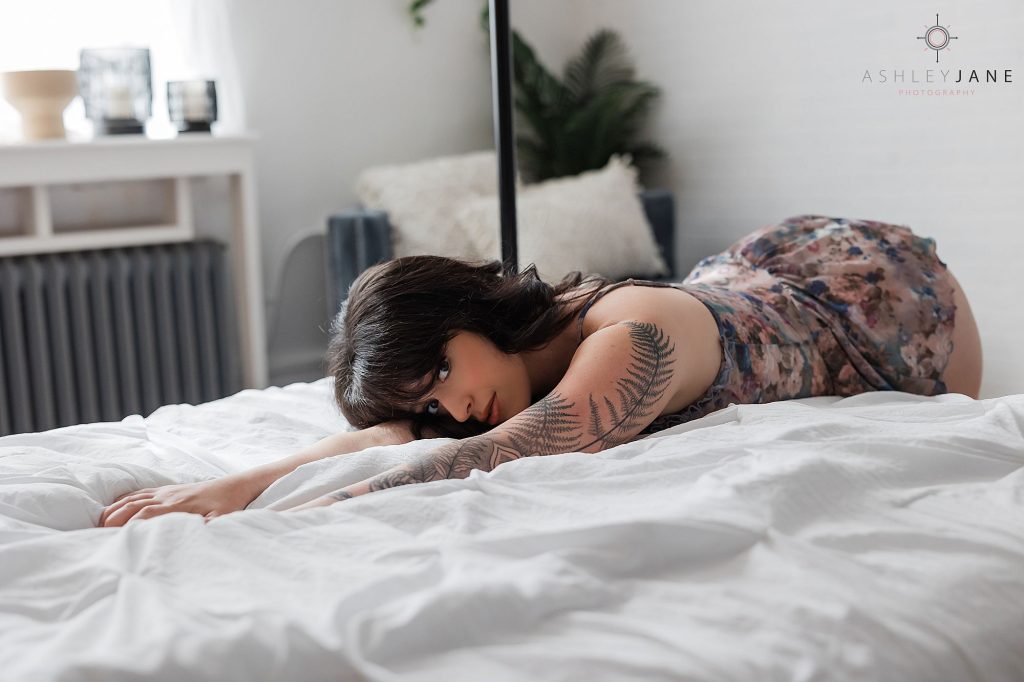 Photo of boudoir model in floral lingerie laying on a bed.