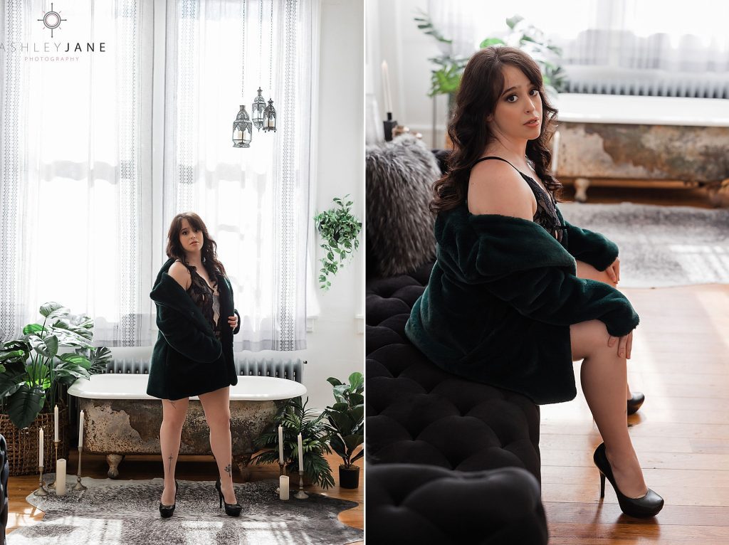 Boudoir model wearing black lingerie and a green fur coat standing in front of claw-foot tun and sitting on couch.