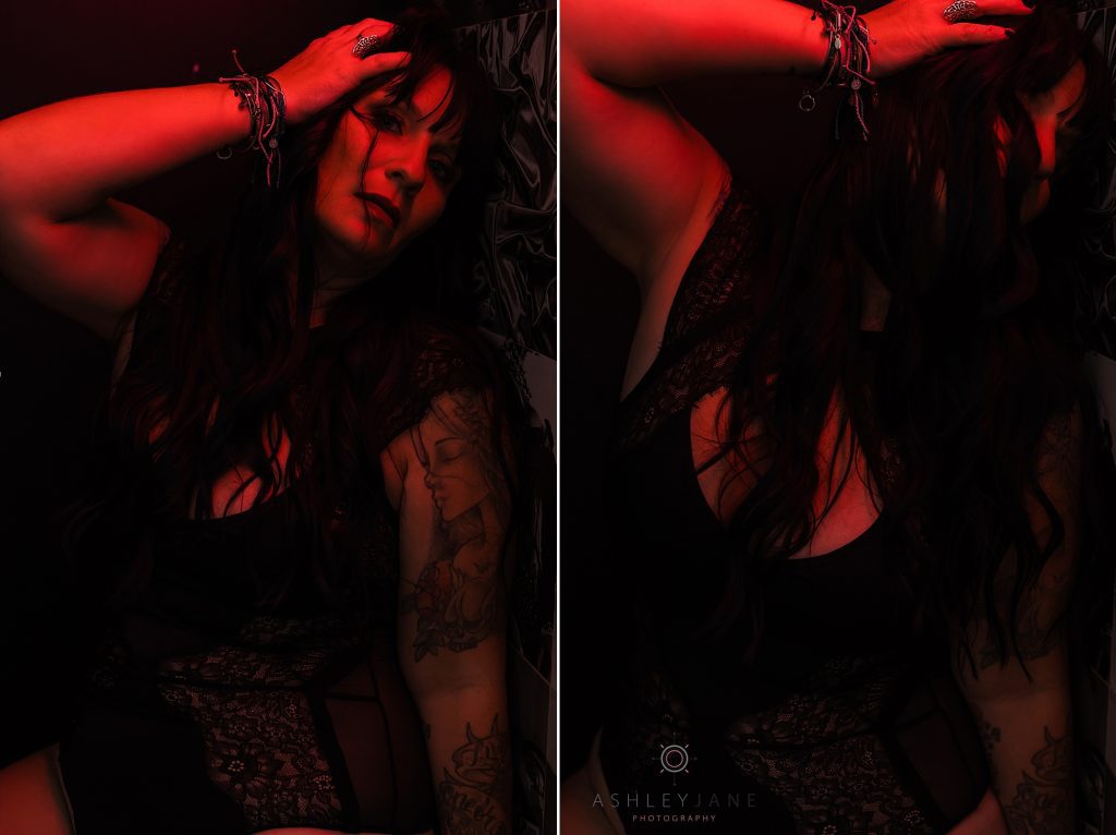 Boudoir model wearing black lacy lingerie standing under bright red light.