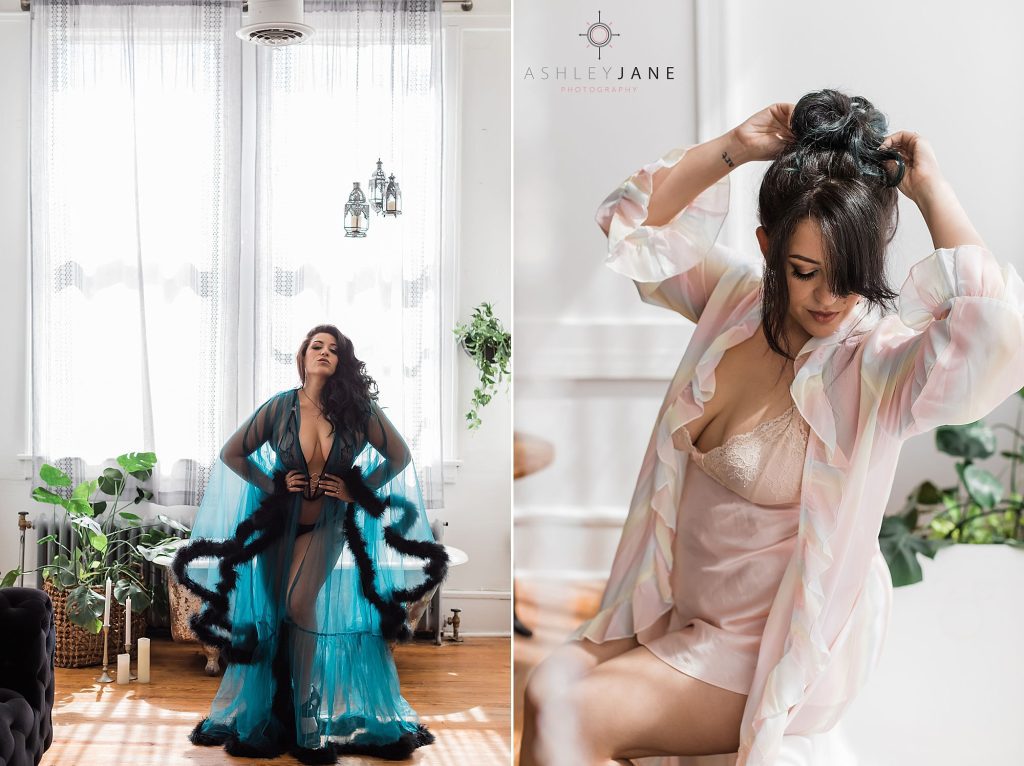 2 boudoir models. The first in standing in front of a claw-foot tub wearing a sheer blue robe with fur trim. the second is sitting on the edge of a claw-foot tub wearing pink lingerie and playing with her hair.